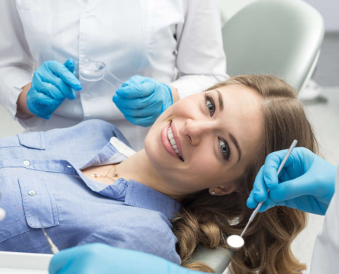 Uśmiechnięta kobieta leży na fotelu dentystycznym i jest przygotowywana do zabiegu reendo, czyli ponownego leczenia endodontycznego.